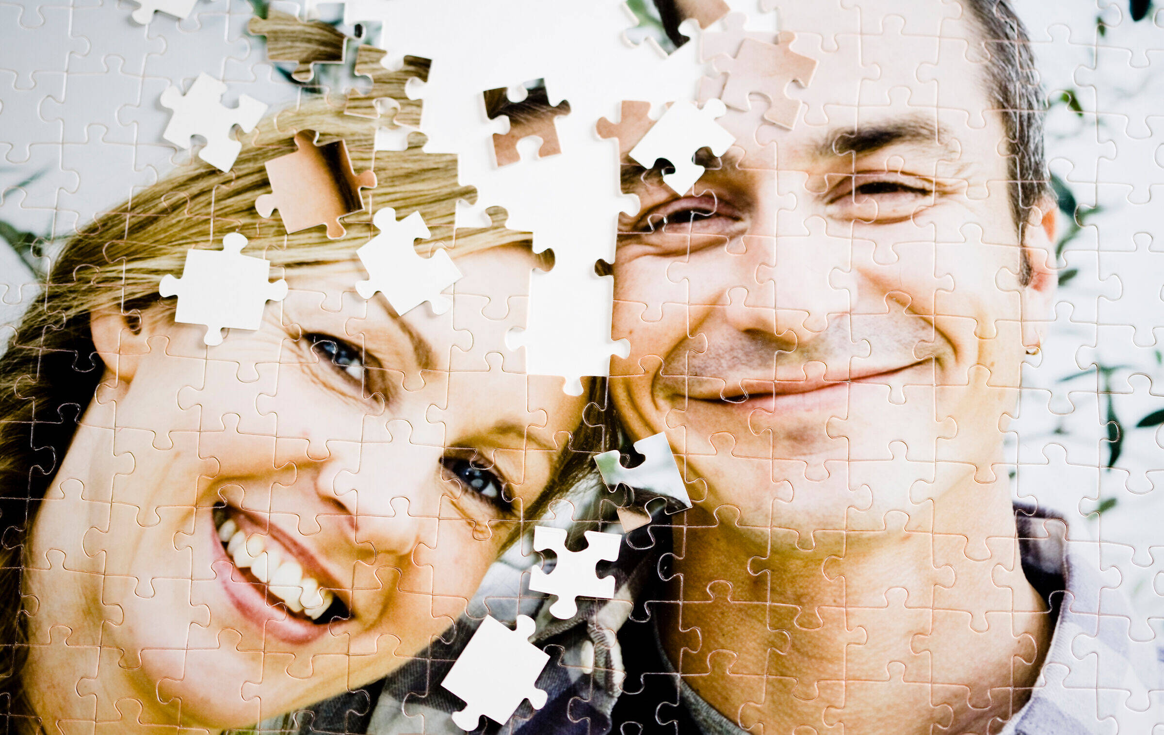 Ein noch unvollständiges Puzzle mit dem Motiv eines in die Kamera lächelnden Paares.