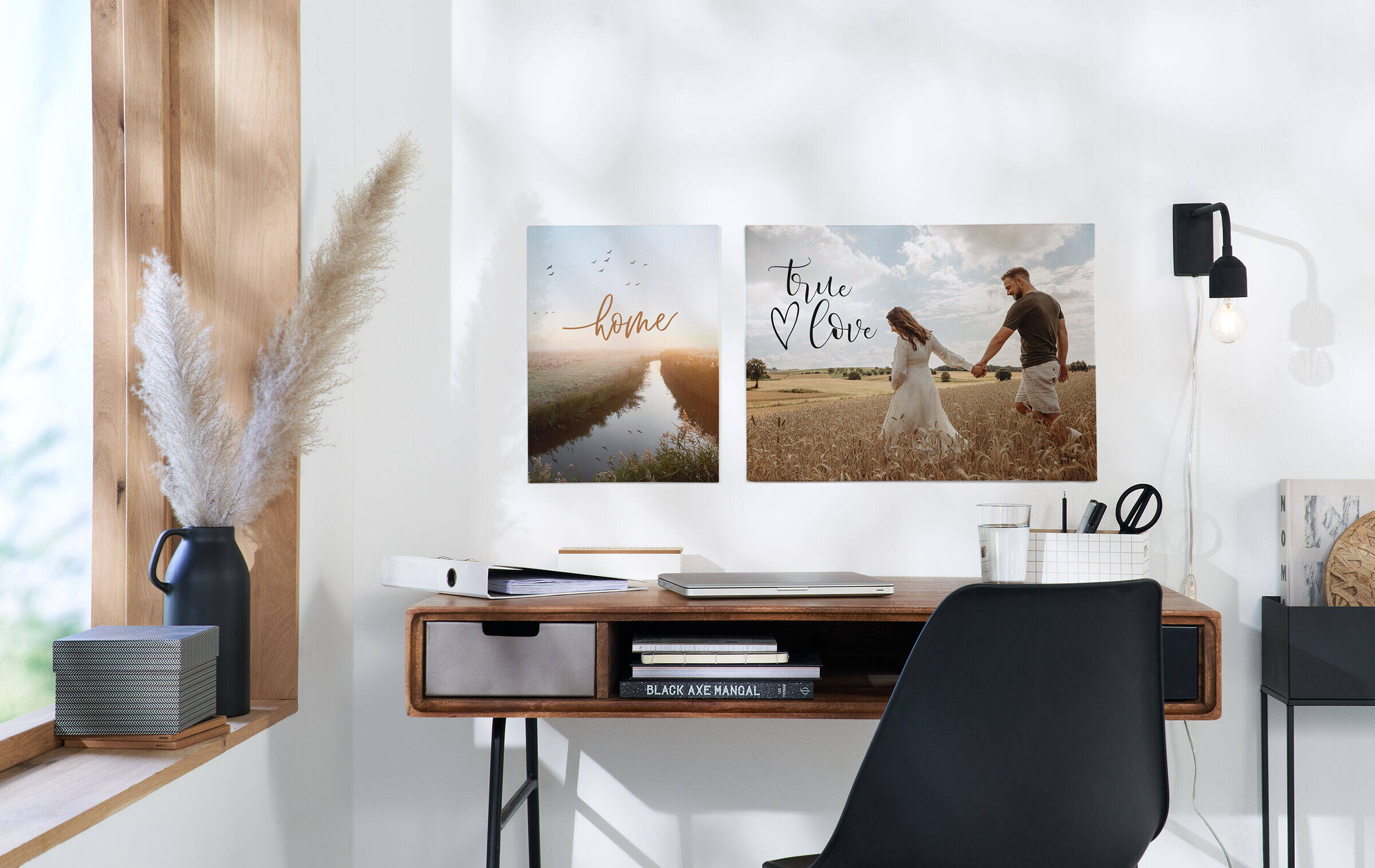 Über einem Schreibtisch hängen zwei Bilder mit Naturaufnahmen. Auf dem rechten sind ein Liebespaar und der Text „True Love“ zu sehen. Links steht „Home“ über einer Naturaufnahme.