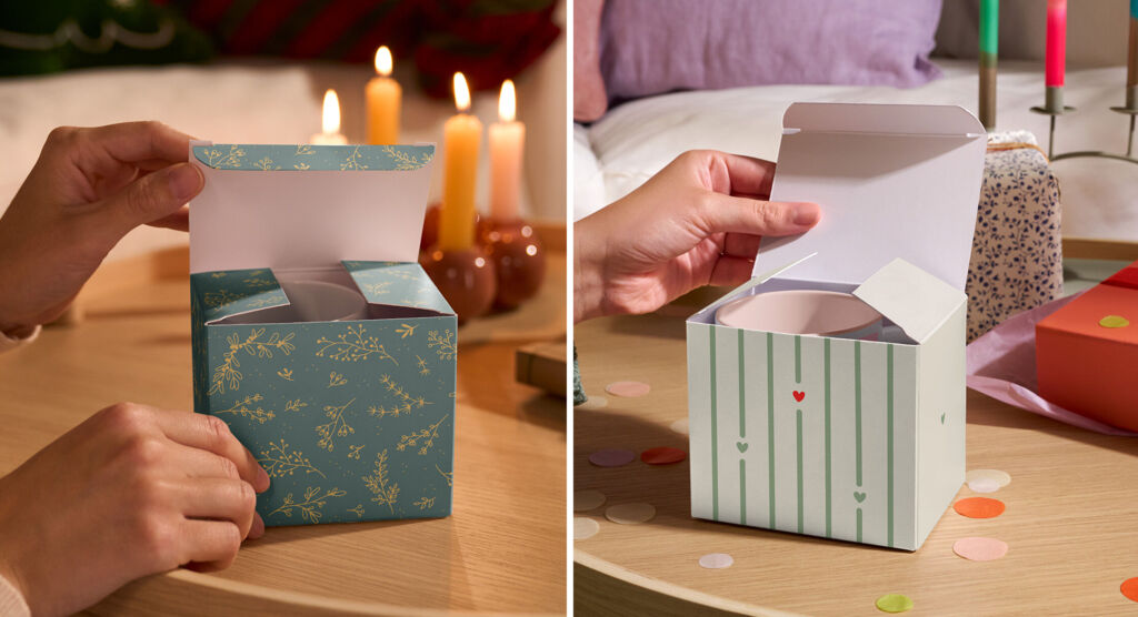 Zwei dekorative Geschenkboxen werden geöffnet: links eine grüne mit floralem Goldmuster, rechts eine weiß-grün gestreifte mit kleinen Herzen