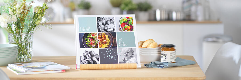 CEWE FOTOBUCH als Reiseführer: Der "Foodie Guide" auf einem Tisch mit Blumen, Fotoapparat und anderen Accessoires.