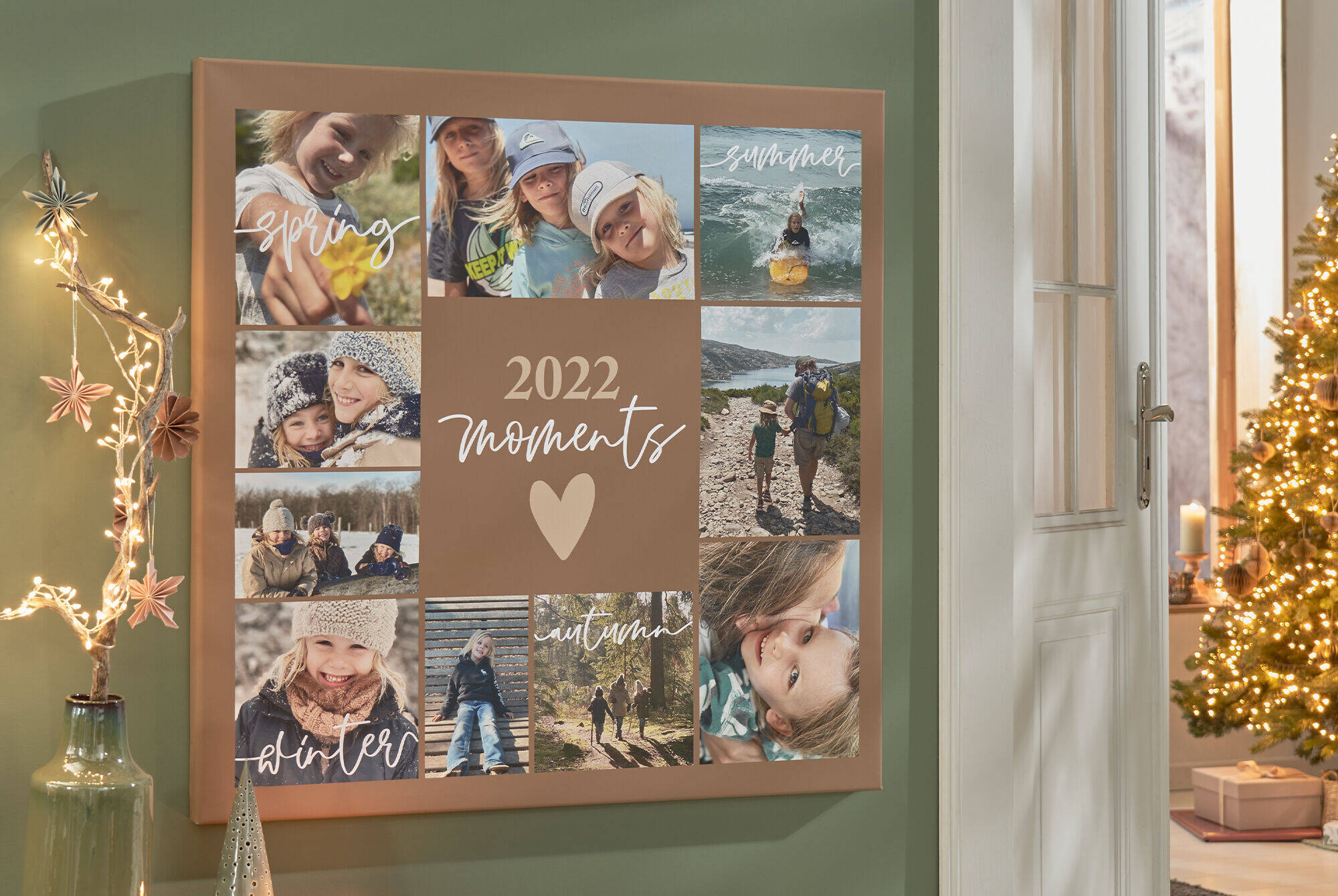 Eine quadratische Leinwand zeigt mehrere Familienmotive als Collage sowie die Aufschrift „2021 Moments“. Daneben fällt der Blick in ein weiteres Zimmer, in dem ein geschmückter Tannenbaum mit Lichterkette steht.