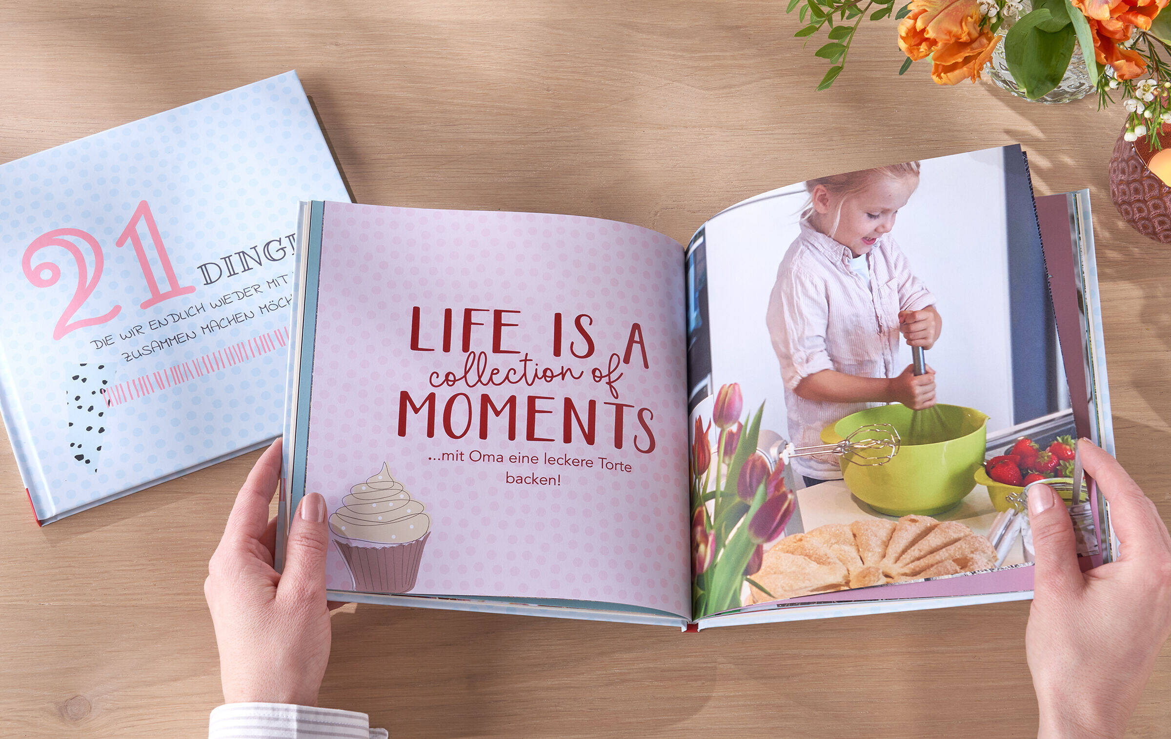 CEWE FOTOBUCH liegt aufgeklappt auf Tisch. Links steht „Life is a collection of moments“, auf der rechten Seite ist das Foto eines Kindes beim Teig rühren zu sehen.