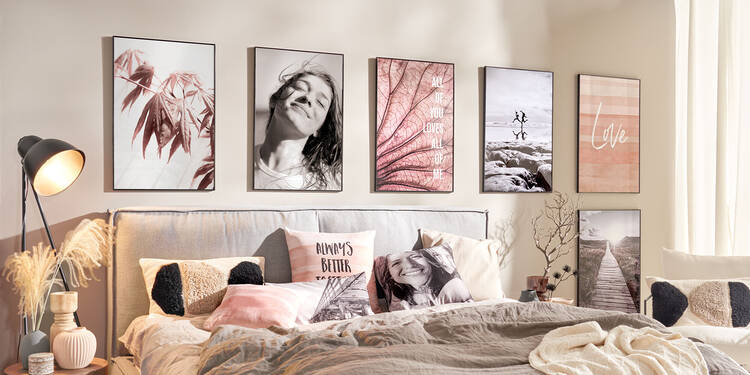 In einem Schlafzimmer hängen sechs große Wandbilder über einem Bett. Darauf sind Nah- und Makroaufnahmen von Pflanzen sowie Schwarz-Weiß-Fotos von Menschen zu sehen. Der Raum ist im Japandi-Stil eingerichtet. Auf dem Bett liegen fünf Kissen, vier davon sind Fotokissen.