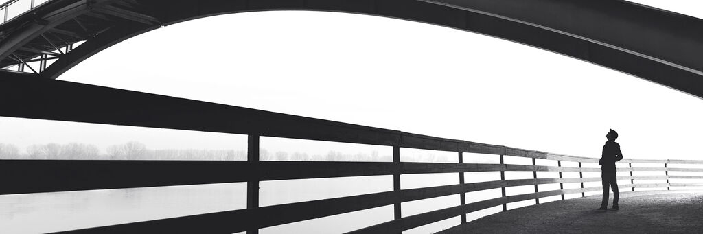 Schwarzweiß-Aufnahme eines Mannes unter einem Brückenbogen.