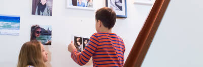 Die Kinder von Anna hängen im Treppenhaus gemeinsam Bilder auf.