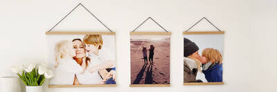 Drei Posterleisten mit Familienfotos hängen an einer Wand.